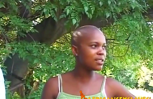 Man dominates over naked black slave with bald head right in backyard