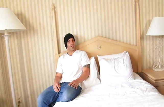 Tattooed guy in cap fucks naked brunette with big tits on the bed