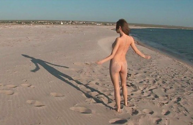 Cameraman films the video of the naked sweetie posing on the beach